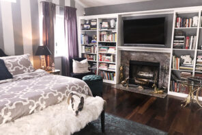 grey and white bedroom with striped accent wall and fireplace and built-in bookshelves