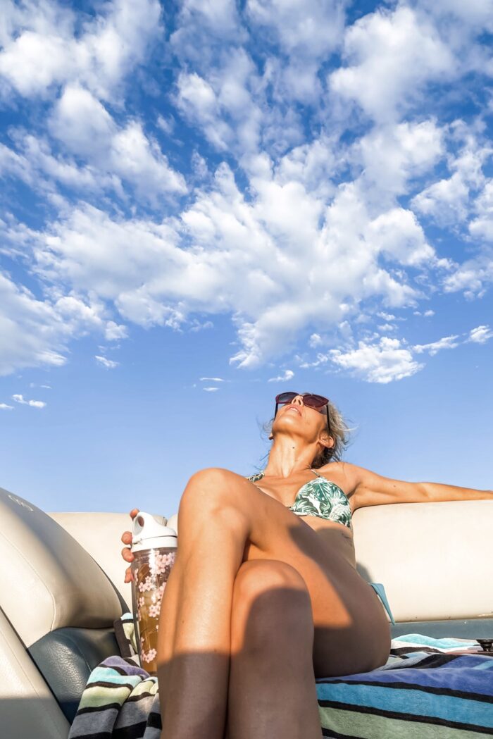 on a boat in lake arrowhead in the summer with blue skies and clouds in a palm leaf bikini