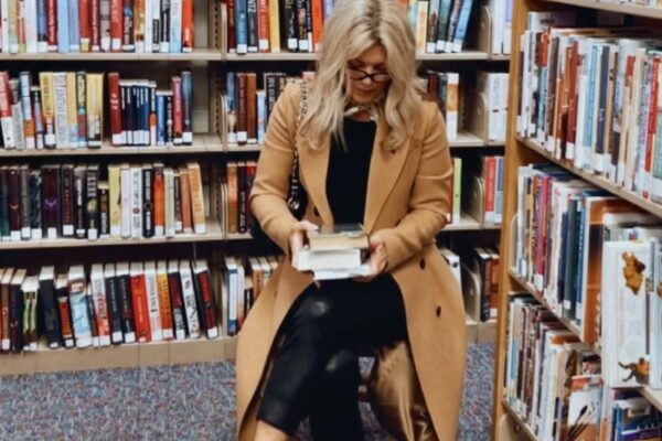 sitting in the library reading, camel coat with snakeskin loafers, black pants and sweter, camel coat, loafers, library aesthetic