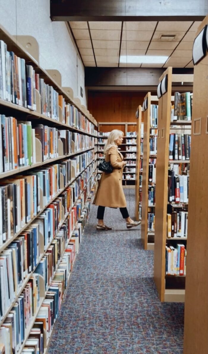 in the library, library books, books, library aesthetic, camel coat, snakeskin loafers, black outfit, faux leather pants, library style, fall style, lake arrowhead library, blonde with glasses, in the library