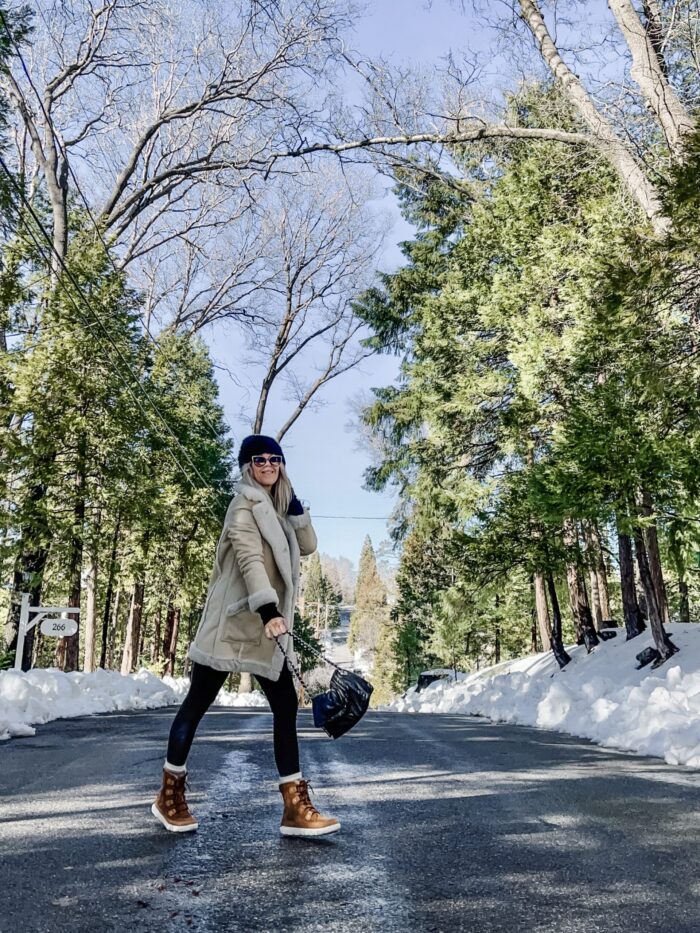 snow style, casual outfit in the snow, winter style, style over 40, cute ways to wear leggings, winter boots, sorels, faux shearling jacket, lake arrowhead, tree lined street