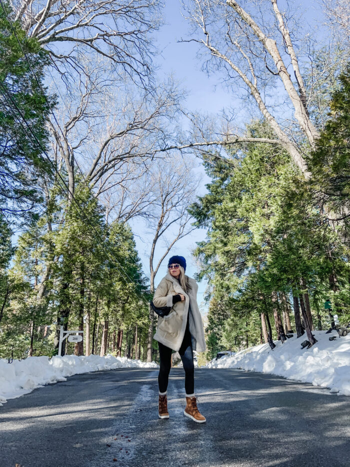 snow style, casual outfit in the snow, winter style, style over 40, cute ways to wear leggings, winter boots, sorels, faux shearling jacket, lake arrowhead, tree lined street