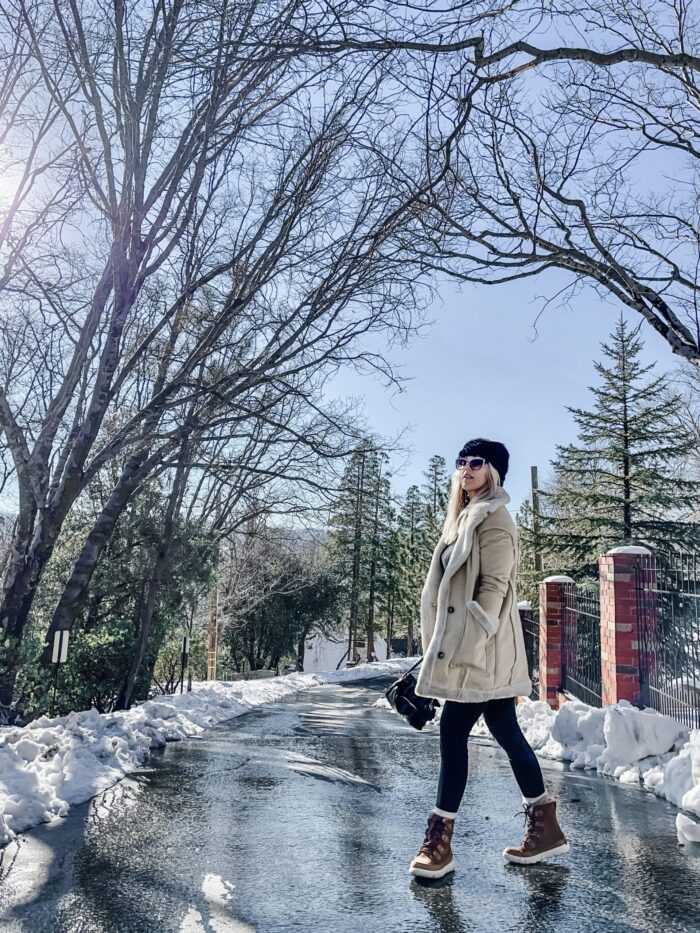 snow style, casual outfit in the snow, winter style, style over 40, cute ways to wear leggings, winter boots, sorels, faux shearling jacket, lake arrowhead, tree lined street