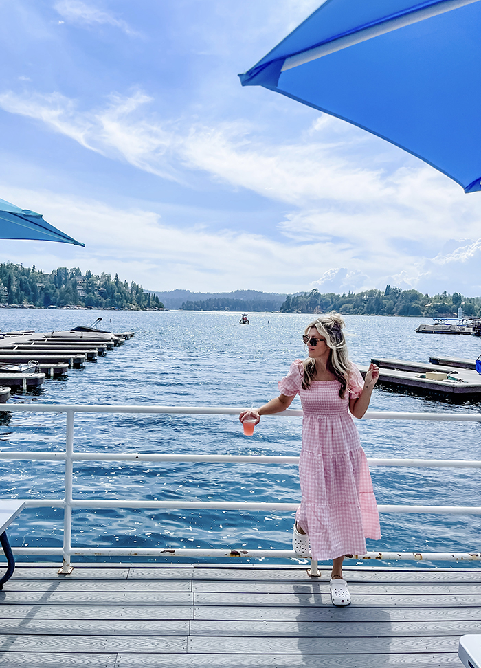 woman in a pink puffy dress with white classic clogs standing on the lake arrowhead docks at the marina in front of the blue lake water and cloudy sky at dogwood dockside jake's on the lake