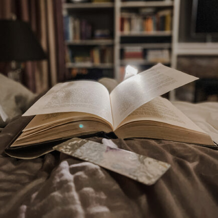 open book on bed with book light