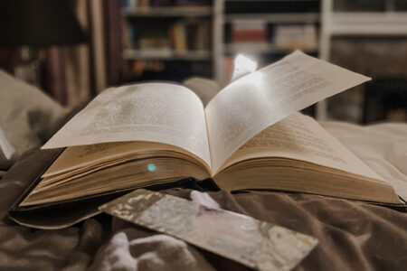 open book on bed with book light