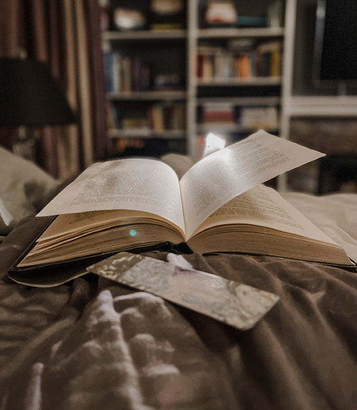 open book on bed with book light