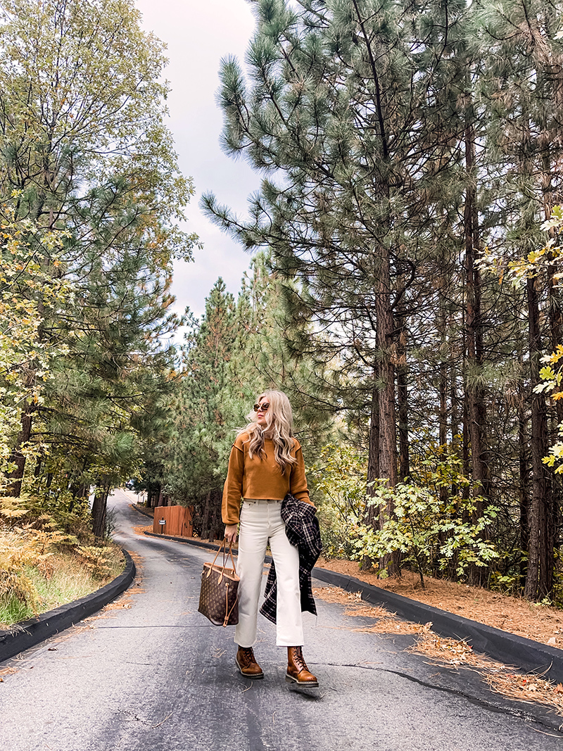 casual fall style in ivory cream and rusty brown tones with a plaid coat and louis vuitton neverfull bag on a wet tree-lined street in lake arrowhead