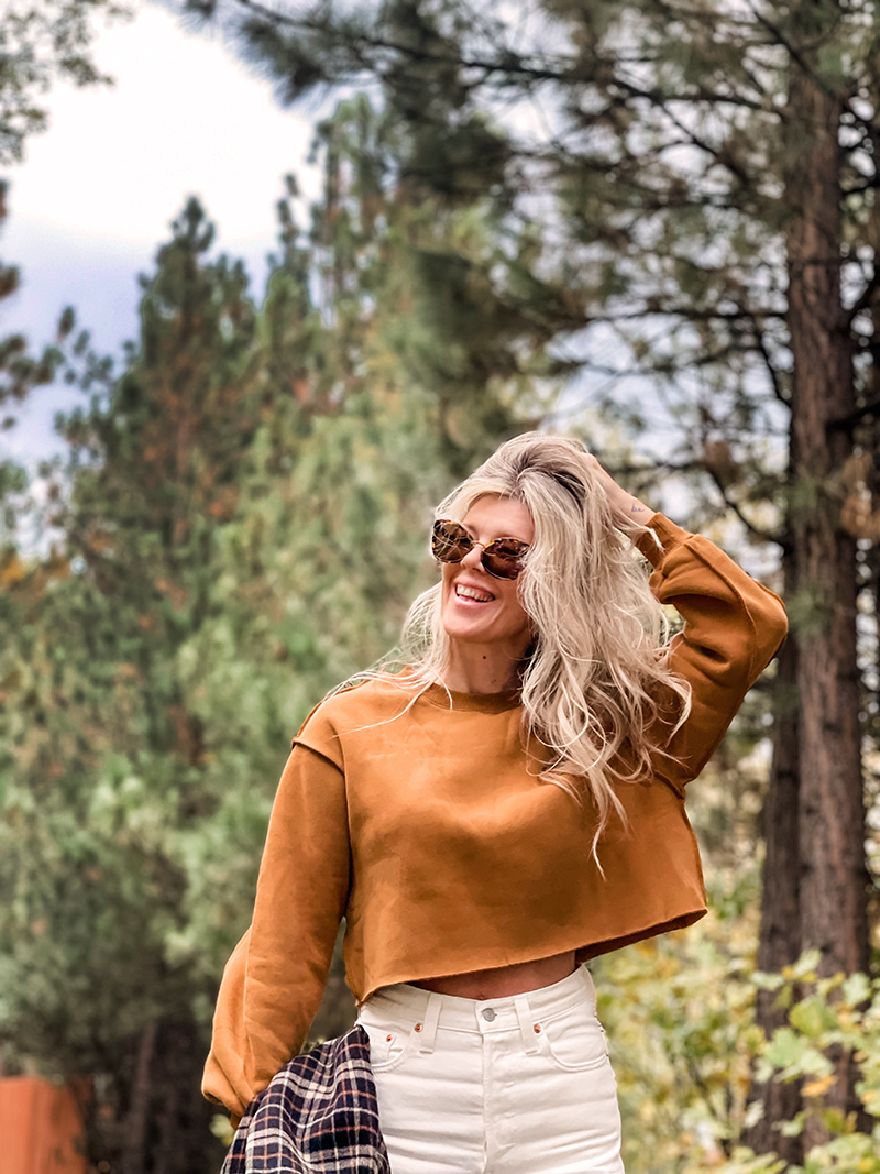 casual fall style in ivory cream and rusty brown tones with a plaid coat and louis vuitton neverfull bag on a wet tree-lined street in lake arrowhead