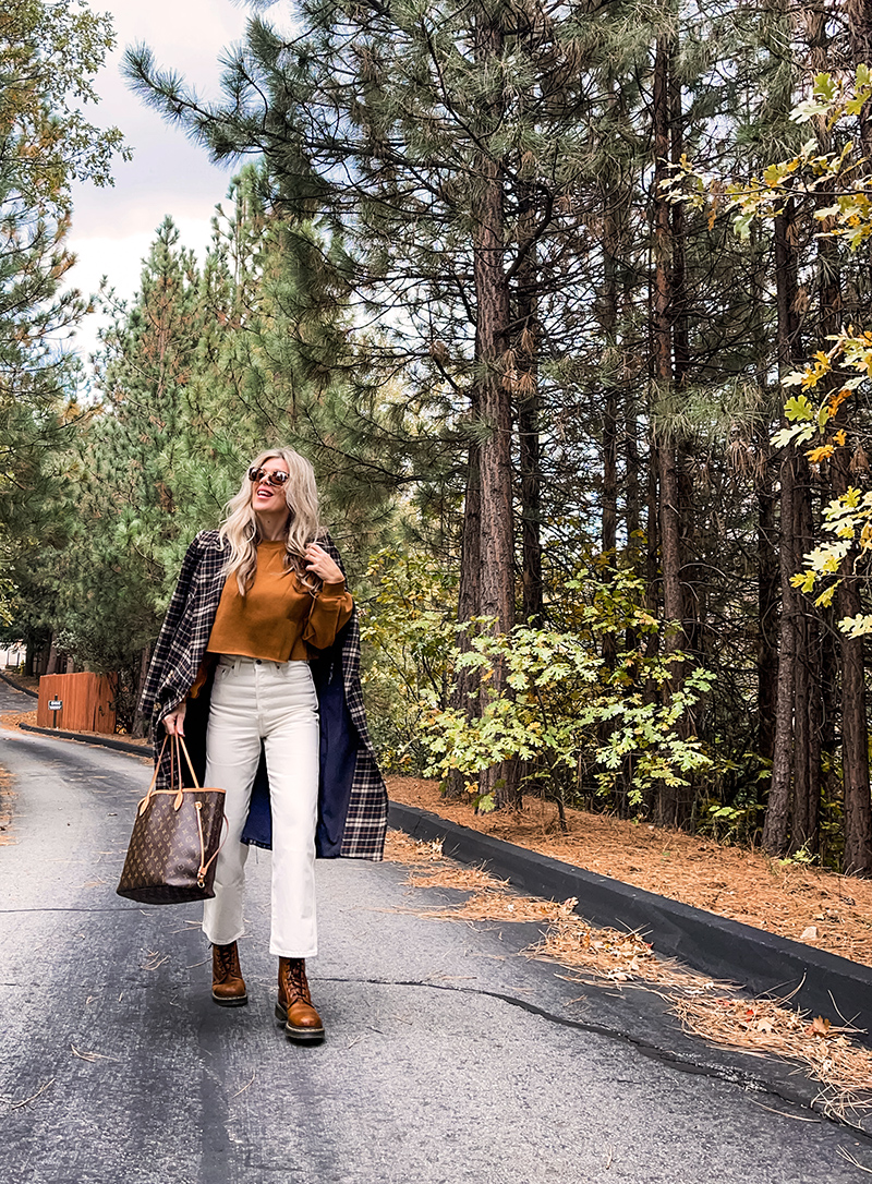 casual fall style in ivory cream and rusty brown tones with a plaid coat and louis vuitton neverfull bag on a wet tree-lined street in lake arrowhead