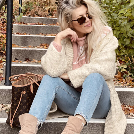 80s look with faded washed high waste jeans and vintage dusty rose mauve 80s sweater with ivory leaves for fall, a louis vuitton neverfull bag, fall style over 40, by lake arrowhead at sunset