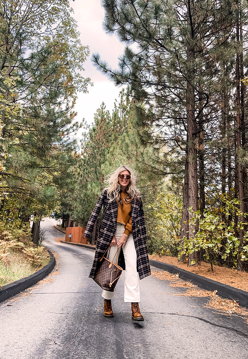 casual fall style in ivory cream and rusty brown tones with a plaid coat and louis vuitton neverfull bag on a wet tree-lined street in lake arrowhead