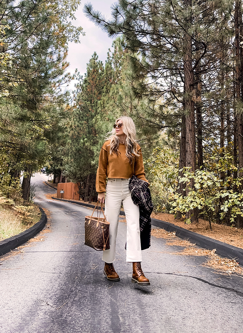 casual fall style in ivory cream and rusty brown tones with a plaid coat and louis vuitton neverfull bag on a wet tree-lined street in lake arrowhead