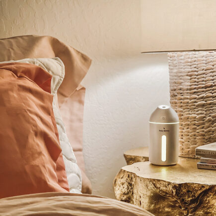 hey dewy small humidifier in white on gold stump nightstand with pink and peach bedding