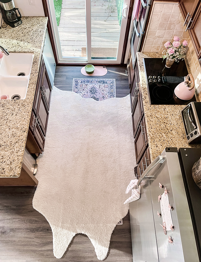 little kitchen with pink accents and faux cowhide rug layered over a narrow runner