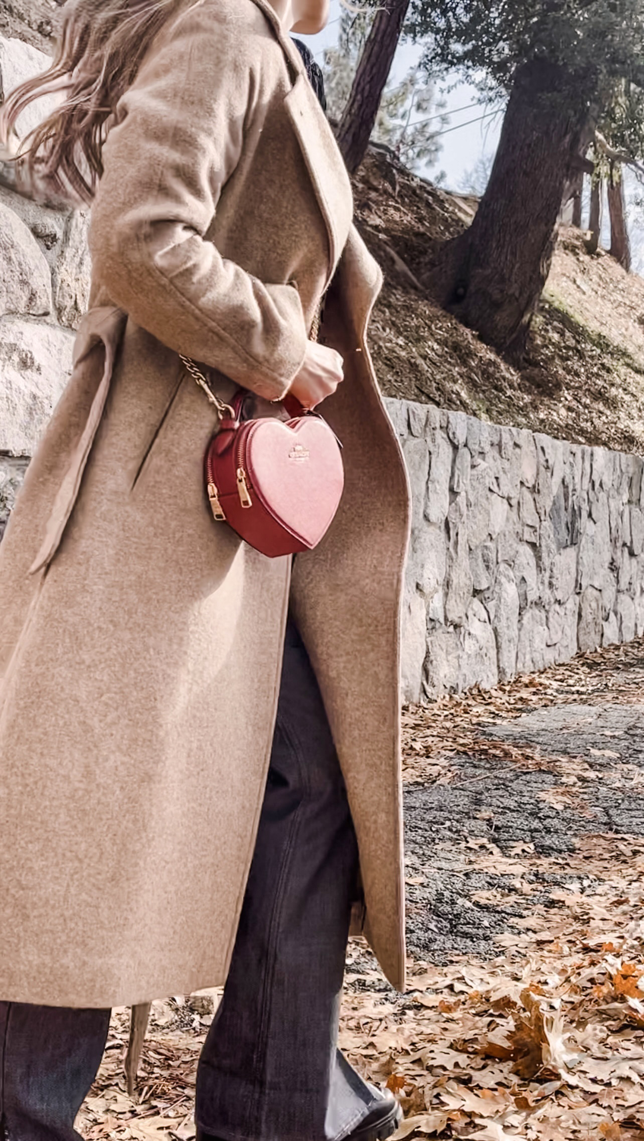 red heart shaped coach bag for valentine's day, casual outfit, vintage levis jeans with a hem slit, chunky loafers, leopard print sweater, red ribbon in her hair, blonde waves, casual winter style