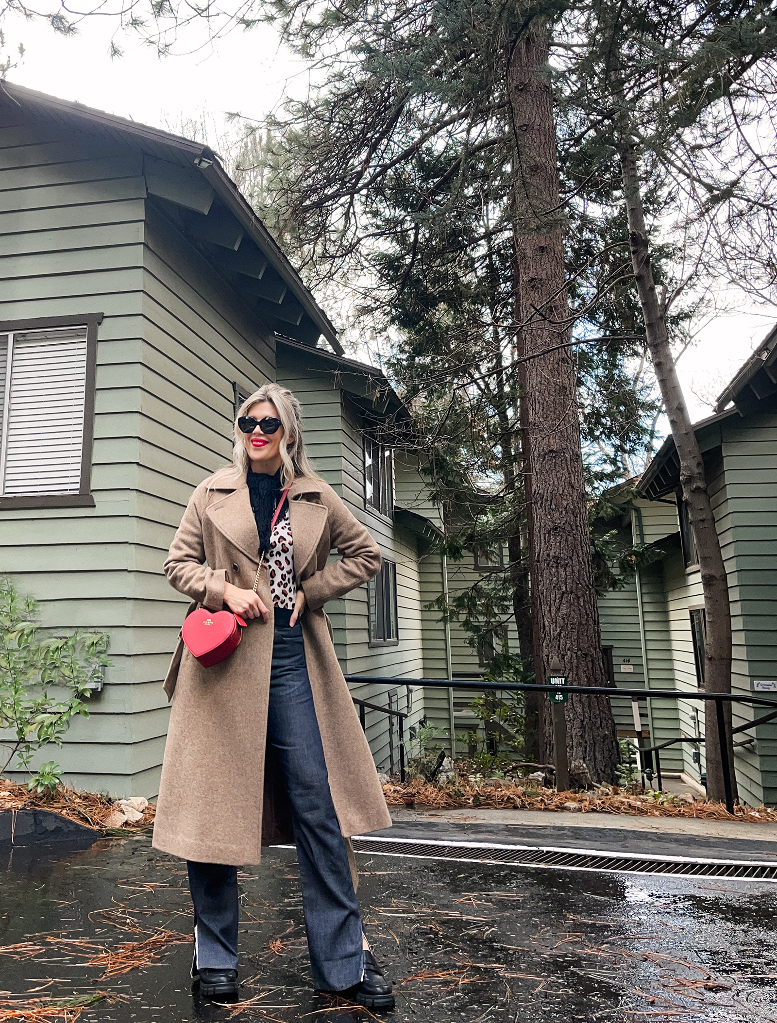 red heart shaped coach bag for valentine's day, casual outfit, vintage levis jeans with a hem slit, chunky loafers, leopard print sweater, red ribbon in her hair, blonde waves, casual winter style