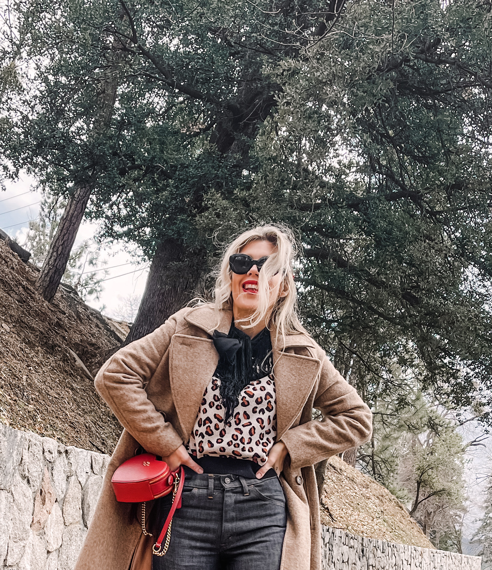 red heart shaped coach bag for valentine's day, casual outfit, vintage levis jeans with a hem slit, chunky loafers, leopard print sweater, red ribbon in her hair, blonde waves, casual winter style