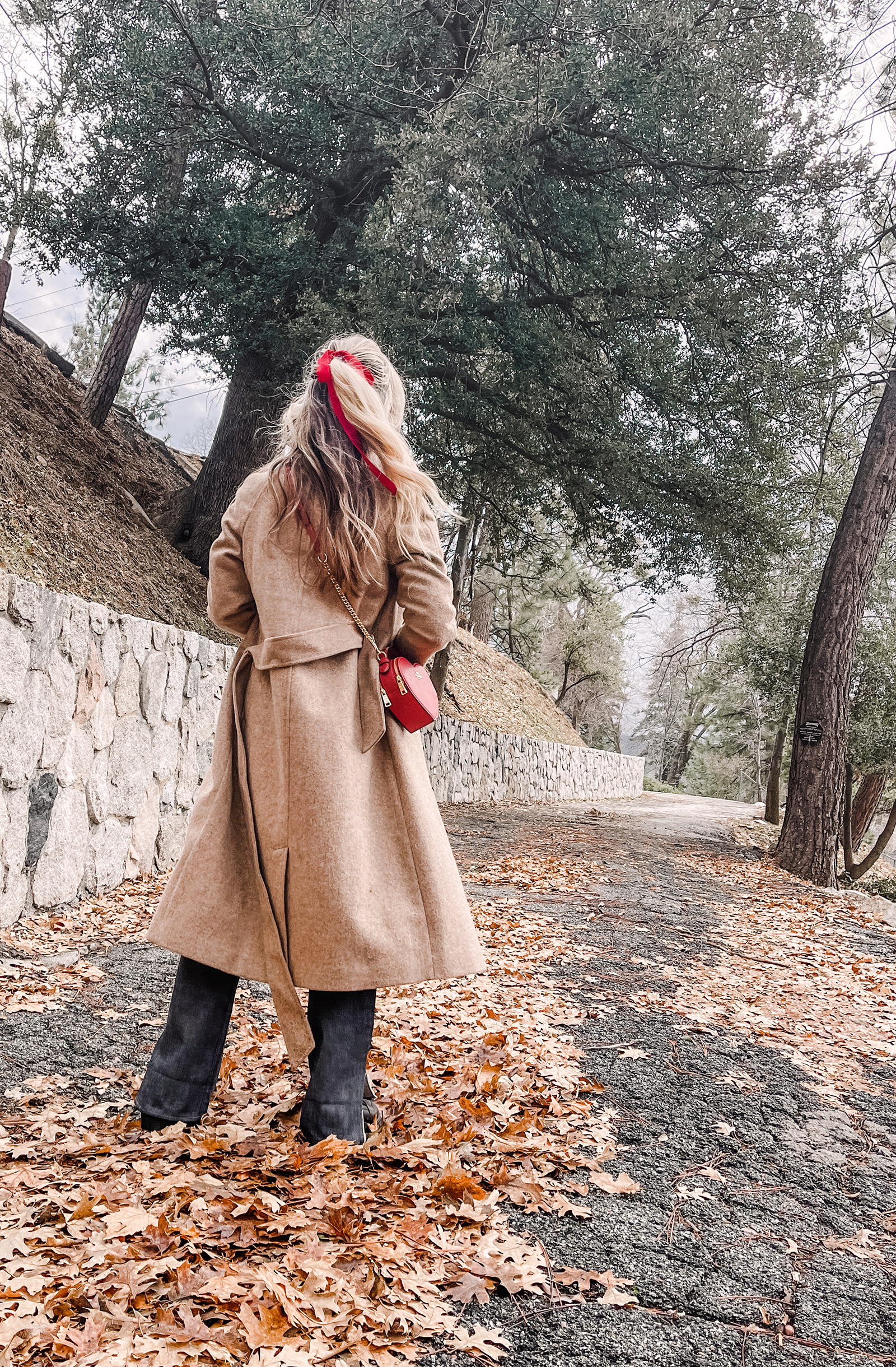 red heart shaped coach bag for valentine's day, casual outfit, vintage levis jeans with a hem slit, chunky loafers, leopard print sweater, red ribbon in her hair, blonde waves, casual winter style