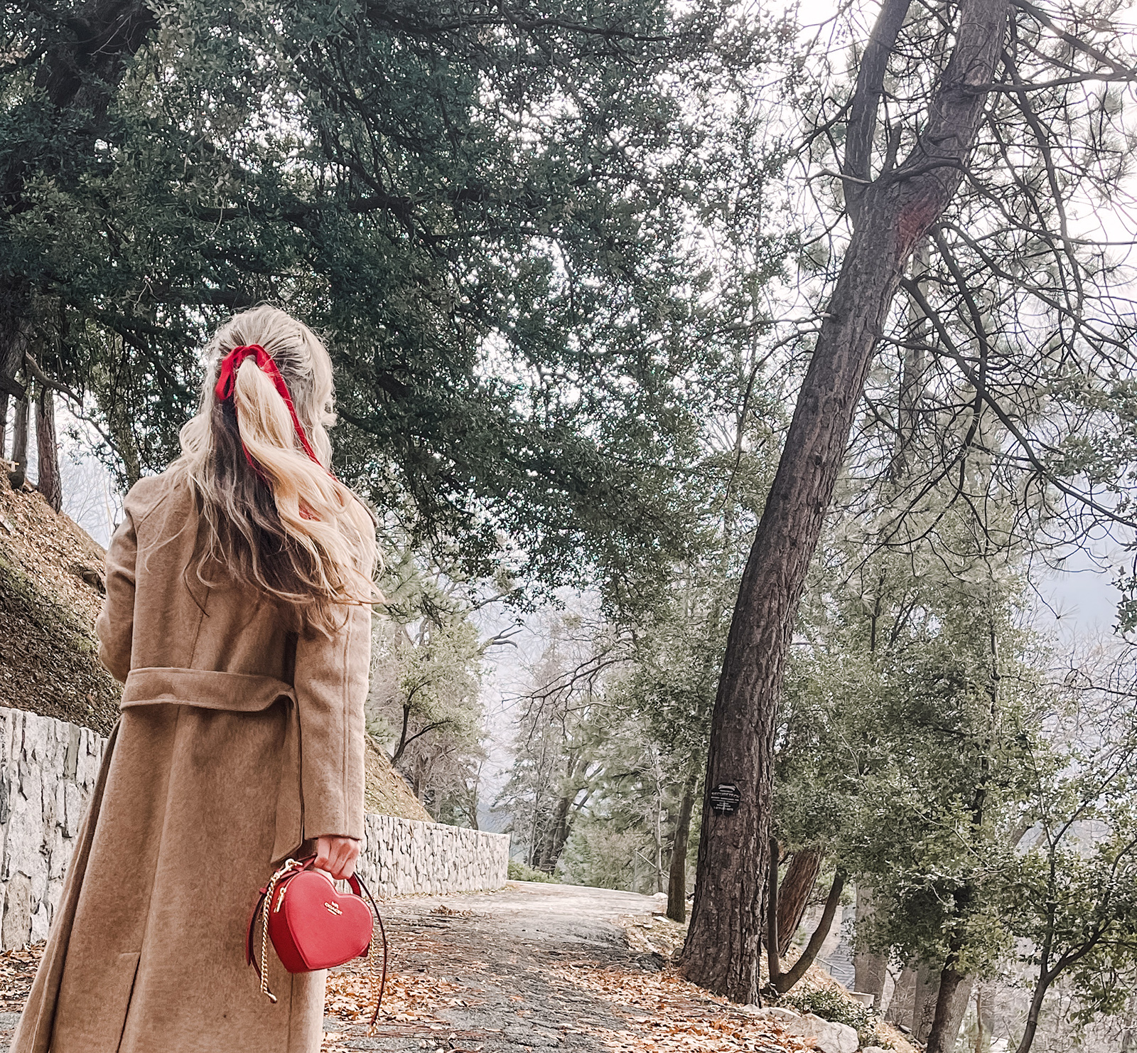 red heart shaped coach bag for valentine's day, casual outfit, vintage levis jeans with a hem slit, chunky loafers, leopard print sweater, red ribbon in her hair, blonde waves, casual winter style