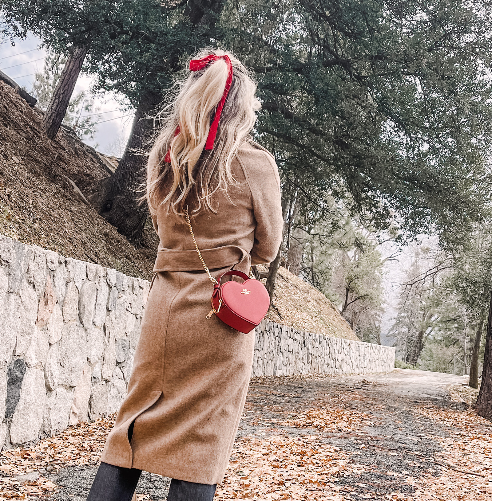 red heart shaped coach bag for valentine's day, casual outfit, vintage levis jeans with a hem slit, chunky loafers, leopard print sweater, red ribbon in her hair, blonde waves, casual winter style