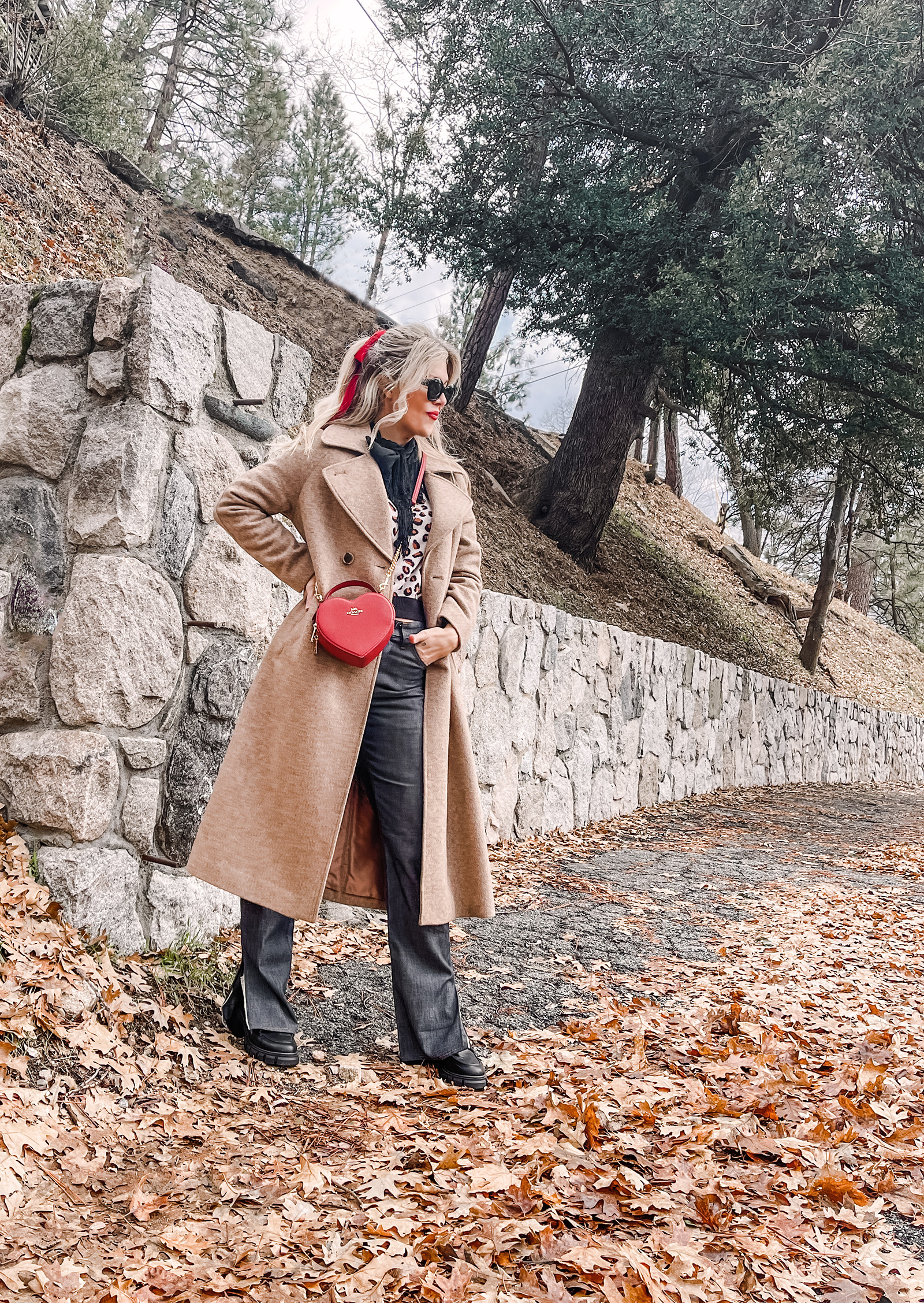 red heart shaped coach bag for valentine's day, casual outfit, vintage levis jeans with a hem slit, chunky loafers, leopard print sweater, red ribbon in her hair, blonde waves, casual winter style