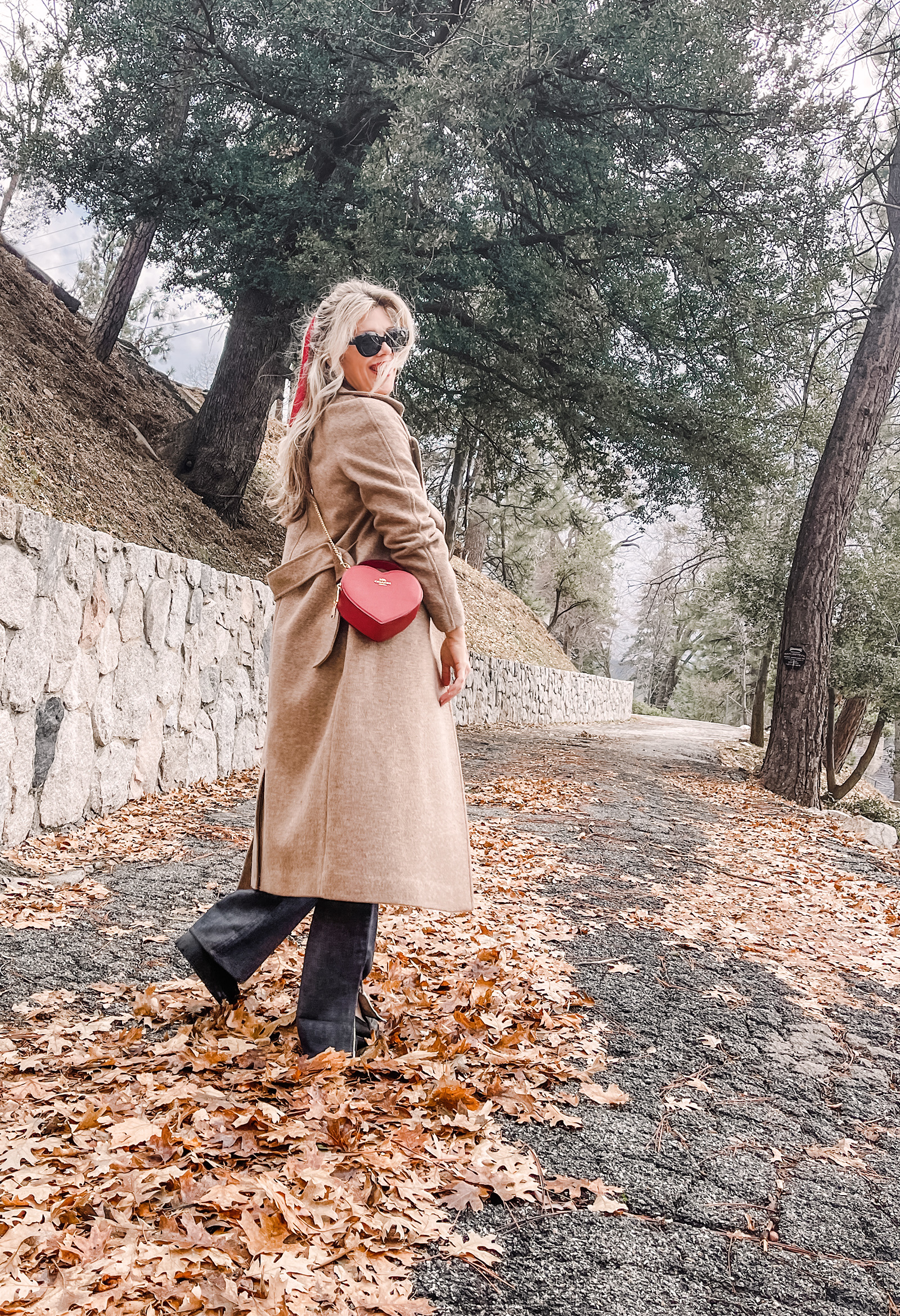 red heart shaped coach bag for valentine's day, casual outfit, vintage levis jeans with a hem slit, chunky loafers, leopard print sweater, red ribbon in her hair, blonde waves, casual winter style