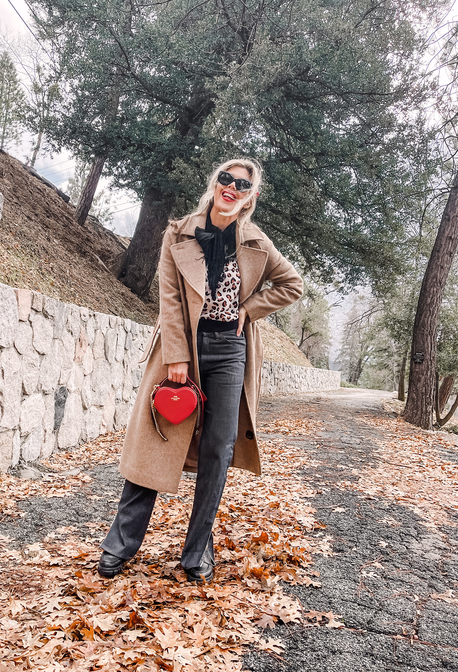 red heart shaped coach bag for valentine's day, casual outfit, vintage levis jeans with a hem slit, chunky loafers, leopard print sweater, red ribbon in her hair, blonde waves, casual winter style