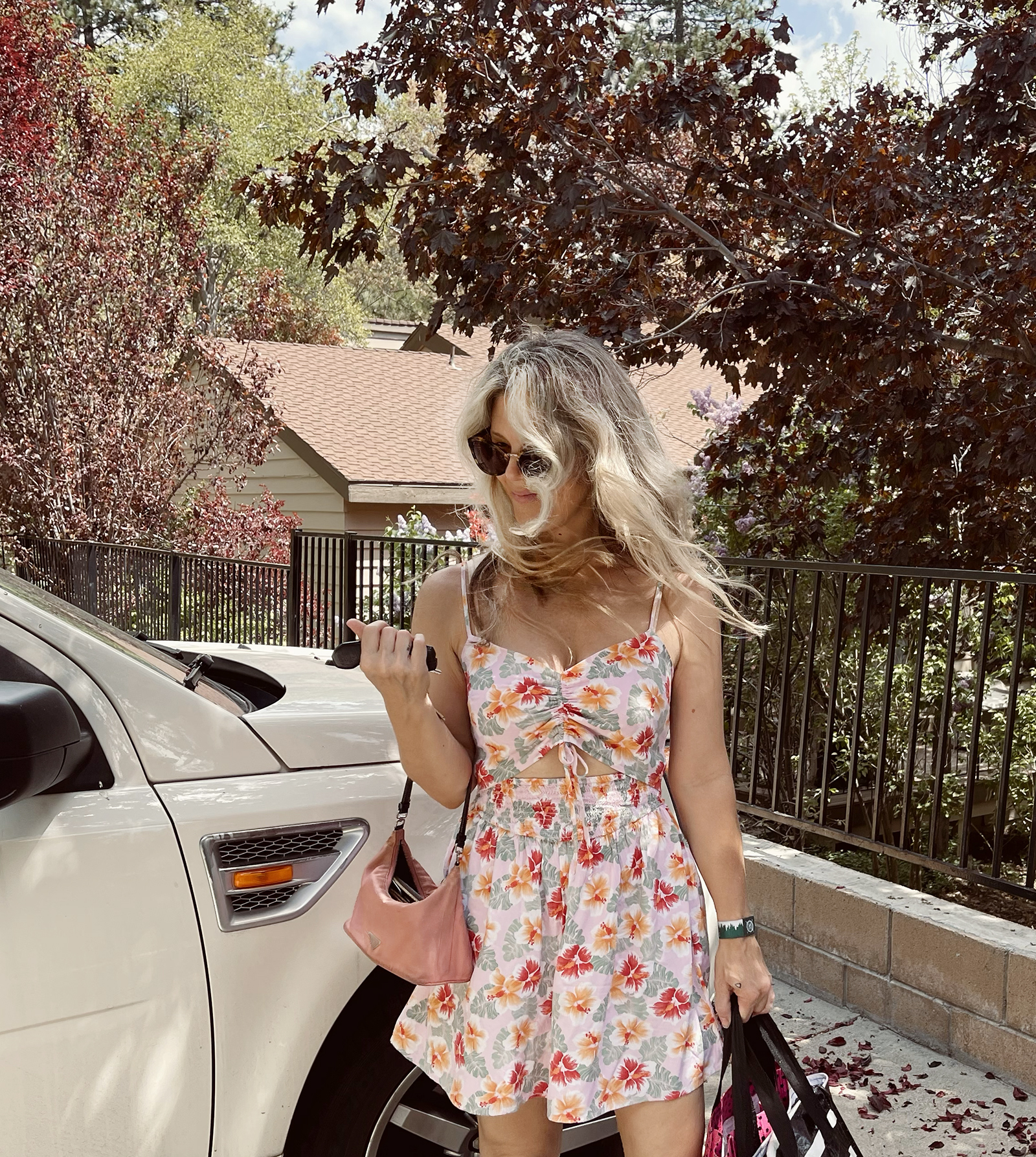 pink tropical print cut out romper for spring and summer cute and feminine with white crocs and vintage nylon prada bag with long dirty blonde beach waves hair style