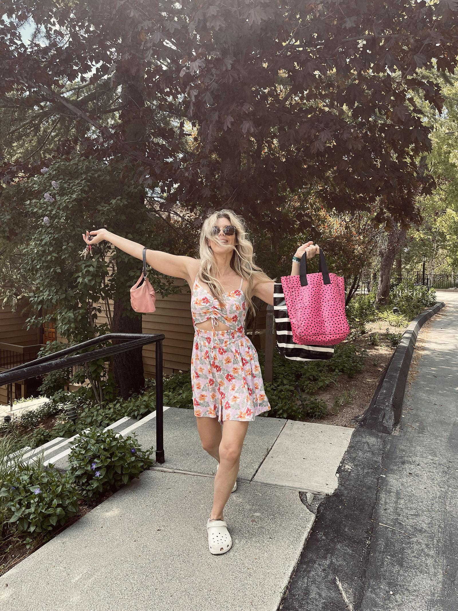 pink tropical print cut out romper for spring and summer cute and feminine with white crocs and vintage nylon prada bag with long dirty blonde beach waves hair style