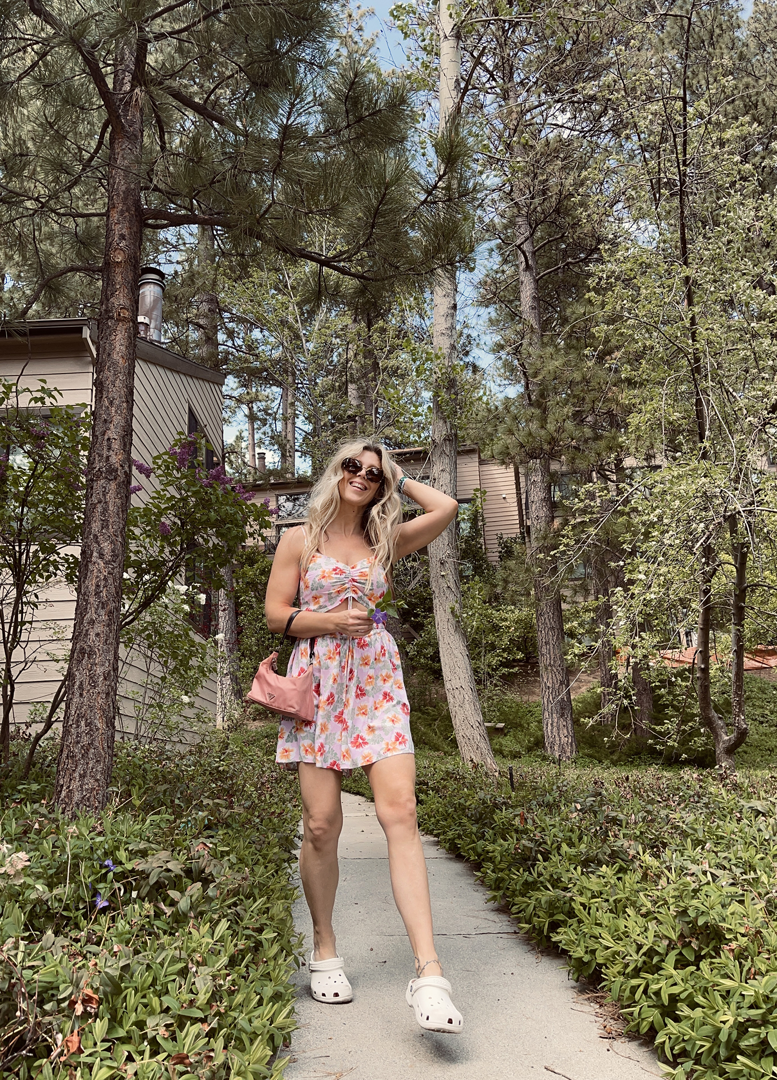 pink tropical print cut out romper for spring and summer cute and feminine with white crocs and vintage nylon prada bag with long dirty blonde beach waves hair style