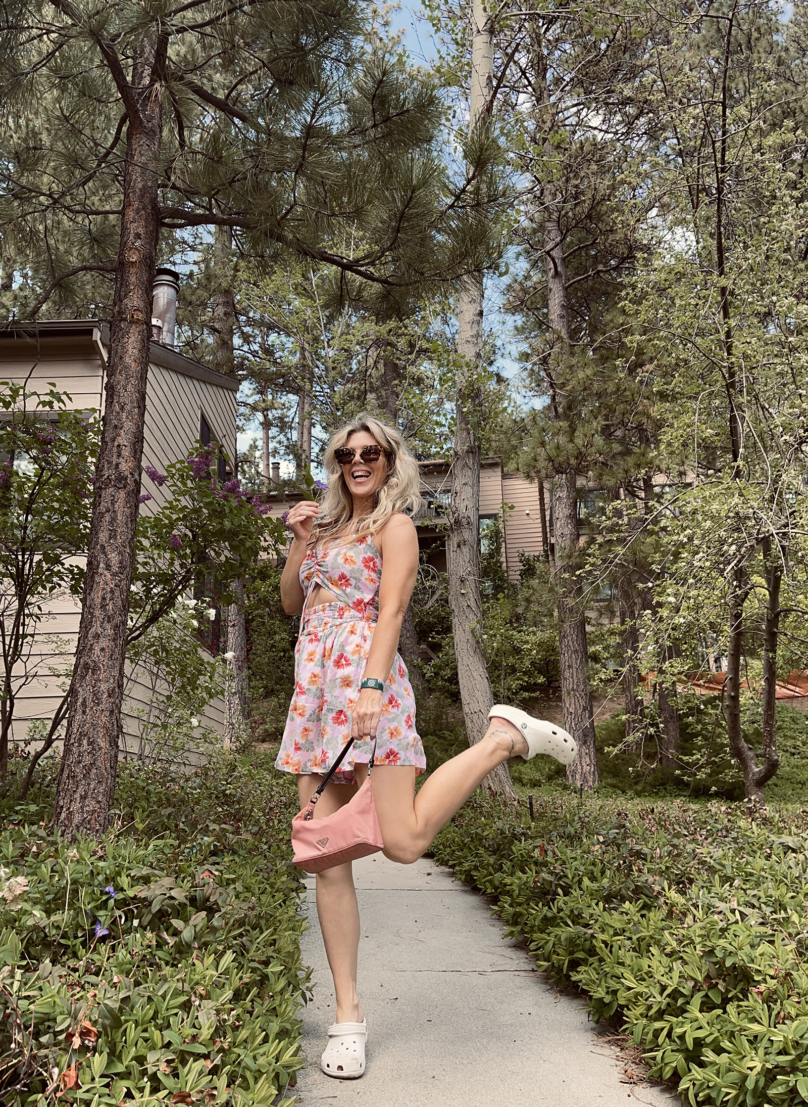 pink tropical print cut out romper for spring and summer cute and feminine with white crocs and vintage nylon prada bag with long dirty blonde beach waves hair style