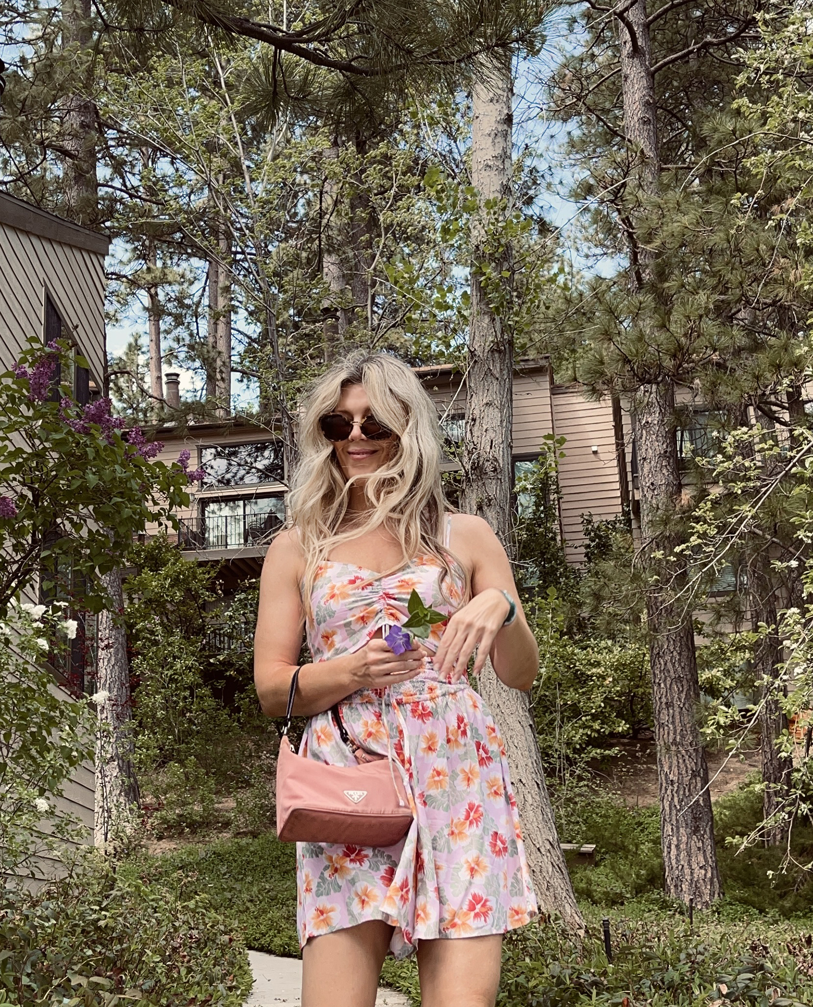 pink tropical print cut out romper for spring and summer cute and feminine with white crocs and vintage nylon prada bag with long dirty blonde beach waves hair style