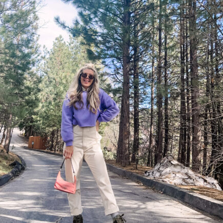 colorful spring outfit with ivory coveralls jumpsuit with lavender cropped sweatshirt pink prada nylon bag and nike sky hi