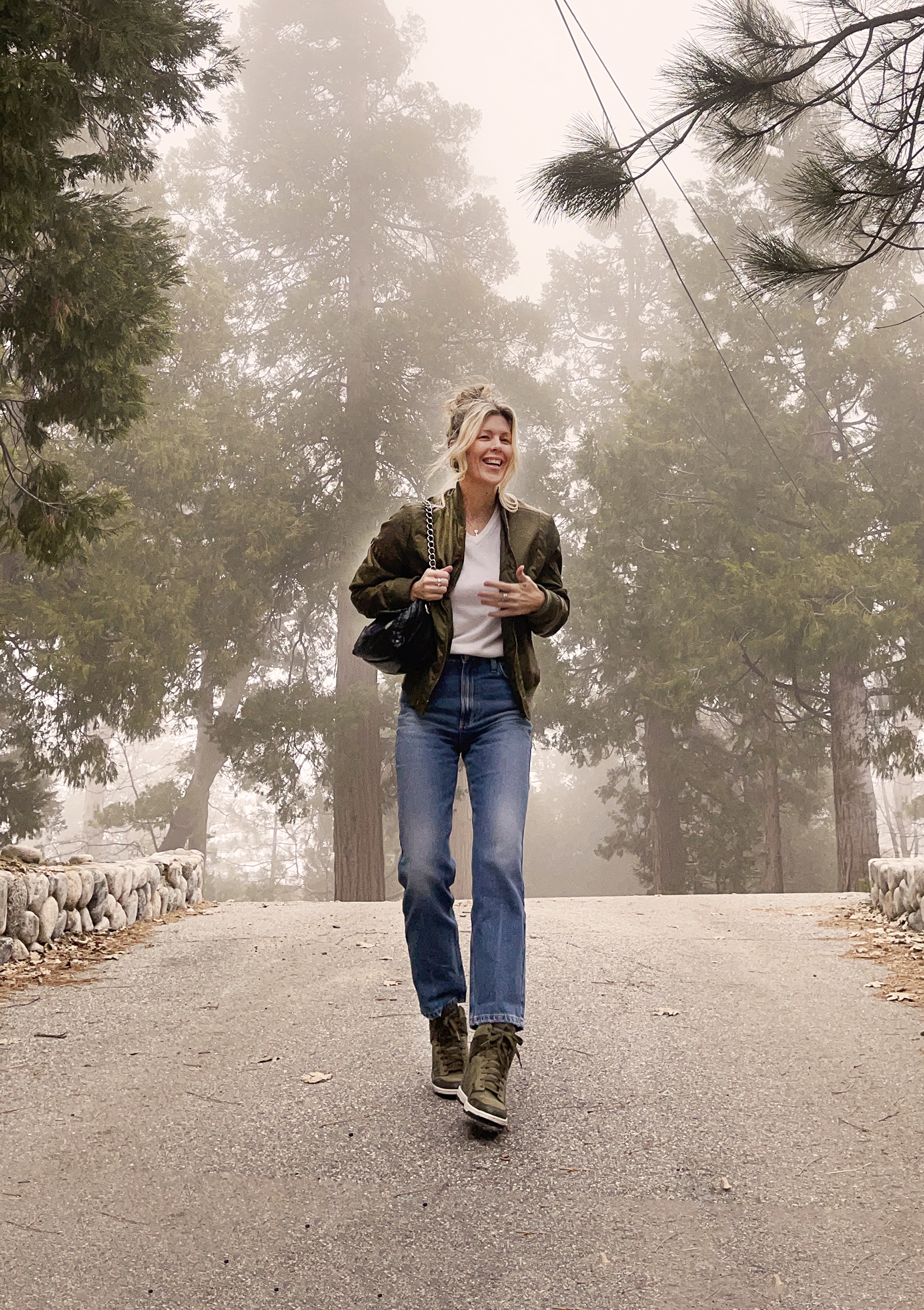 casual denim style, straight classic high waist ankle jeans, army green jacket and nike shoes with vintage white sweater and black pillow bag, spring 2024 style in the forest fog