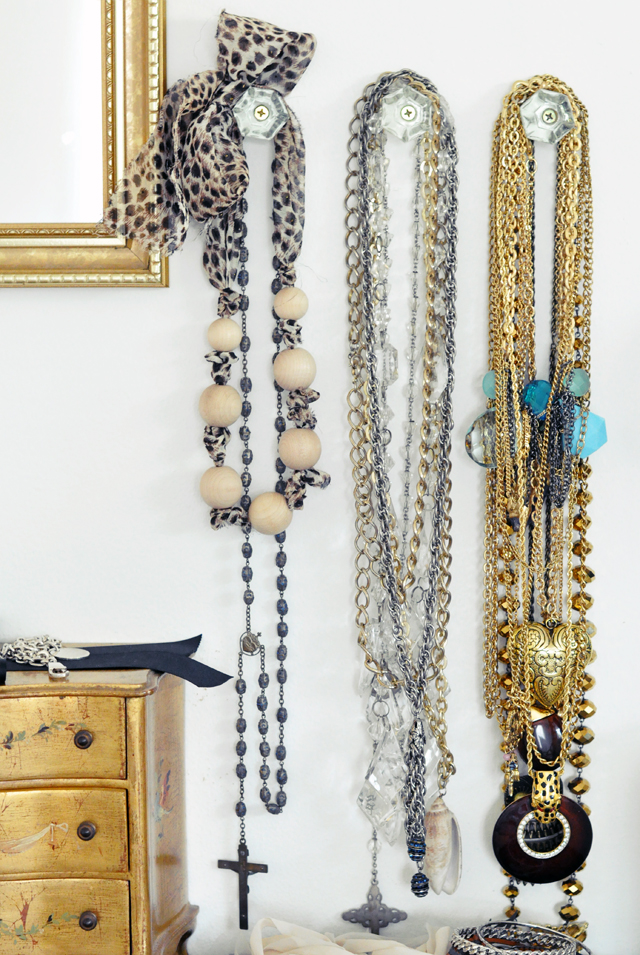 Necklaces hanging from crystal knobs on the wall